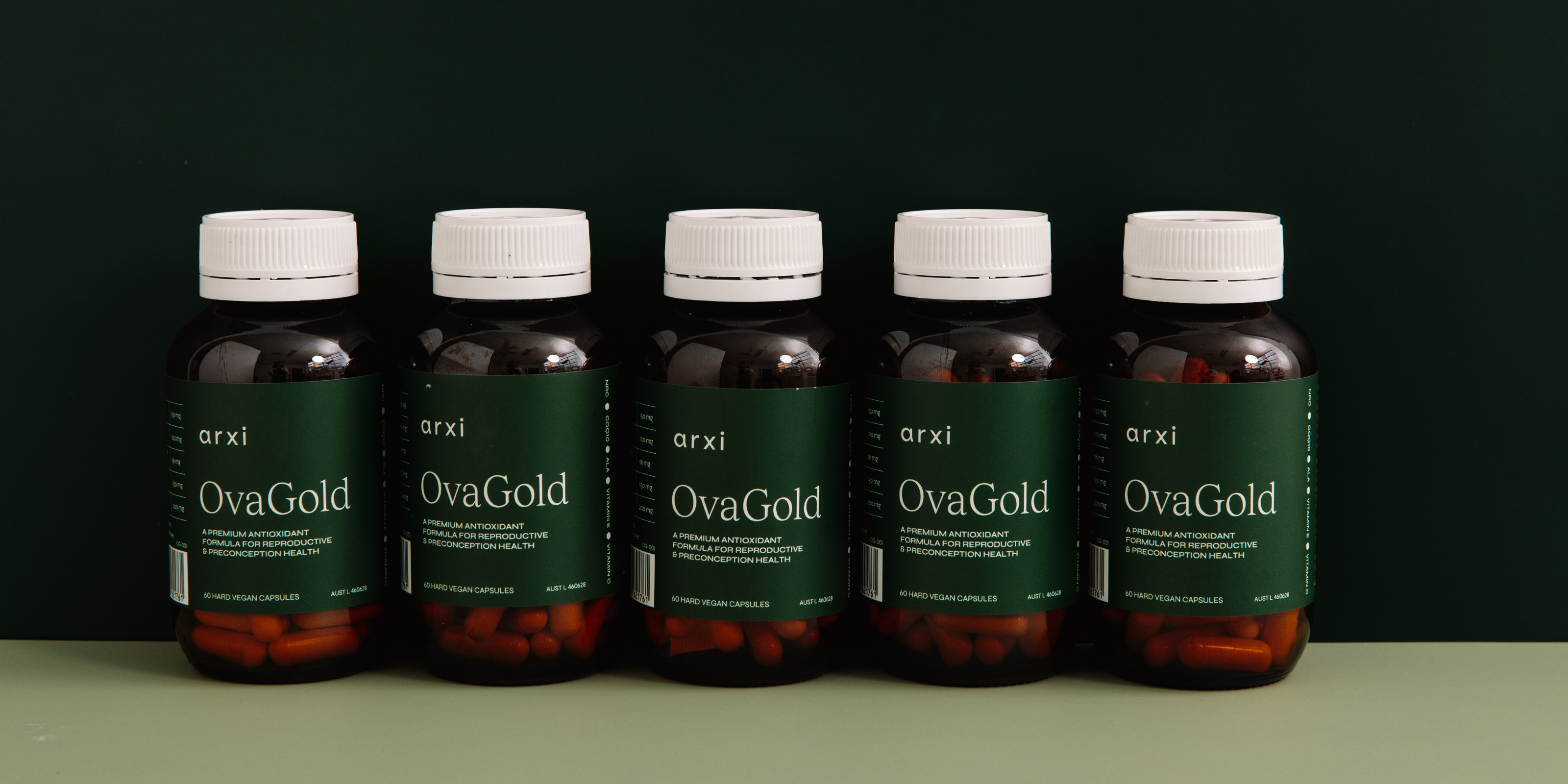Five bottles of OvaGold supplement on a green background